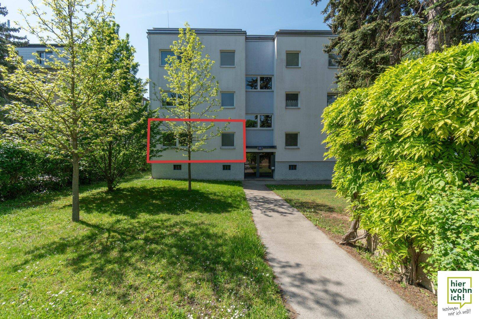 Außenansicht des Mehrfamilienhauses mit gepflegter Grünfläche und einem Zugangsweg.