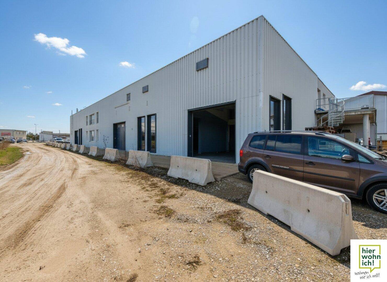 Außenansicht einer modernen Gewerbehalle mit Wellblechfassade und breiter Zufahrt, ideal für Logistik.