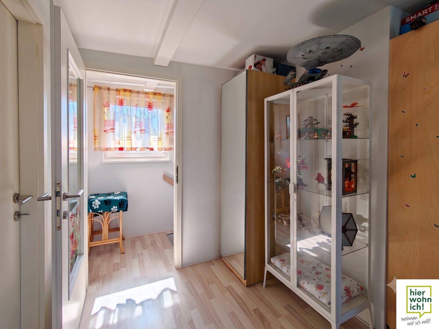 Heller Flur mit Laminatboden, Vitrine und Zugang zum Treppenbereich.