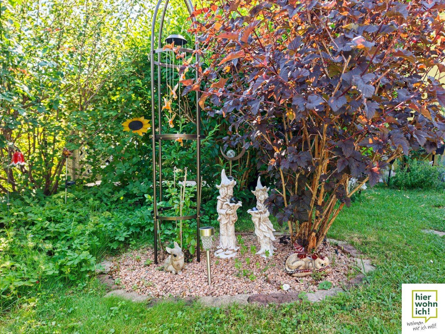 Detailansicht eines Gartenteils mit Zwergenfiguren, Pflanzen und Kiesbeet.