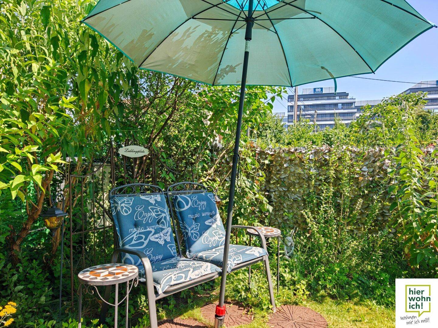 Gemütlicher Sitzbereich im Garten mit Sonnenschirm und üppiger Bepflanzung, ideal zum Entspannen.