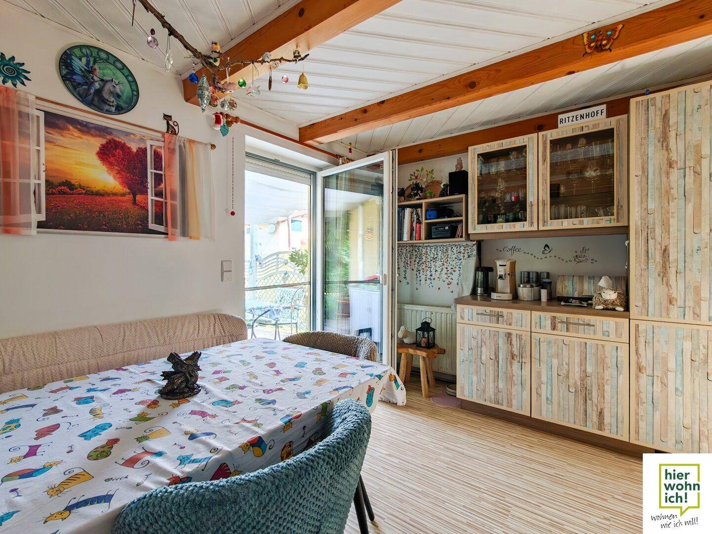 Gemütlicher Essbereich mit Holzbalken, rustikalen Möbeln und Zugang zur Terrasse.