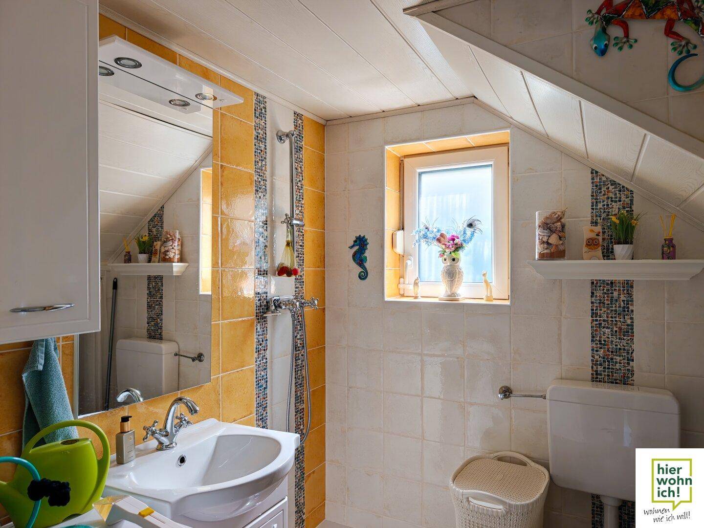 Badezimmer im Dachgeschoss mit gelben Fliesen, Dusche und Fenster für Tageslicht.