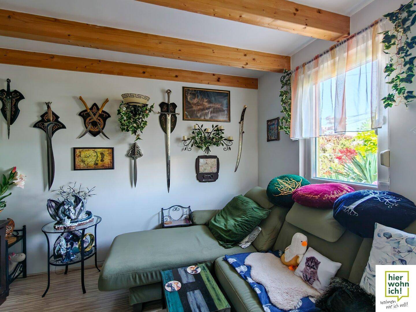 Gemütliches Wohnzimmer mit Chaiselongue, sichtbaren Holzbalken an der Decke und dekorativen Schwertern.