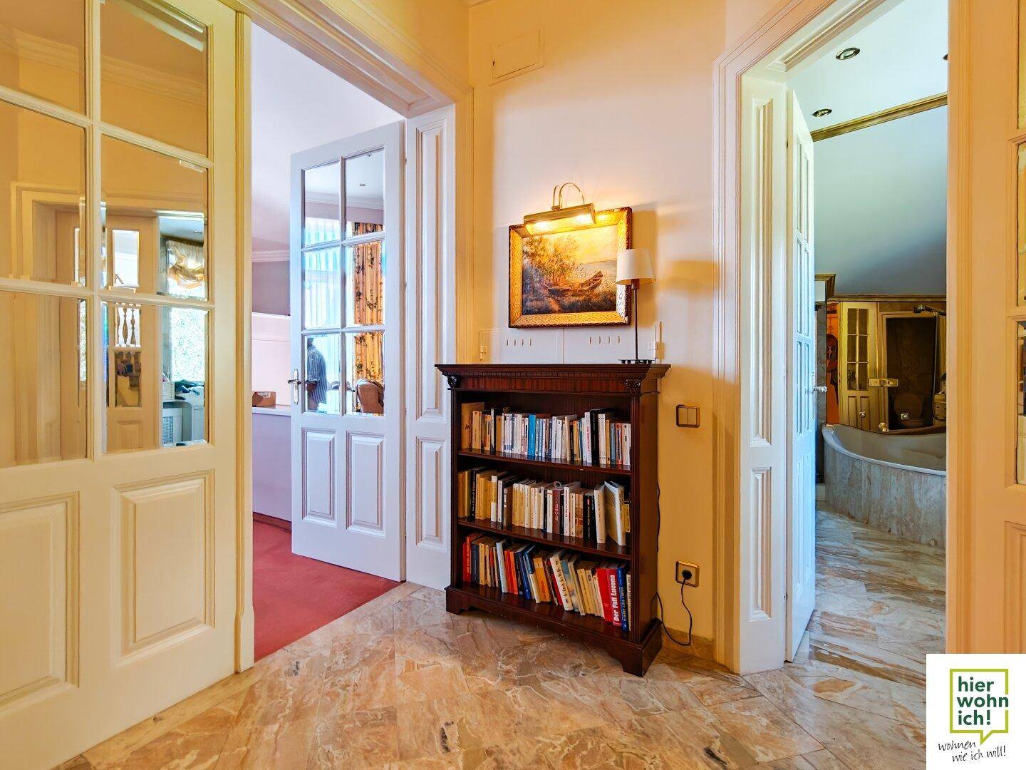 Eingangsbereich mit Bücherregal, Marmorboden und eleganten Glastüren.