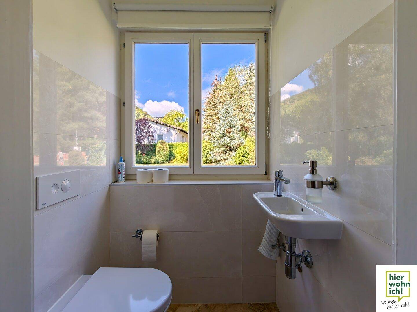 Modernes Gäste-WC mit Fenster, weiß gefliesten Wänden und einem kleinen Waschbecken.