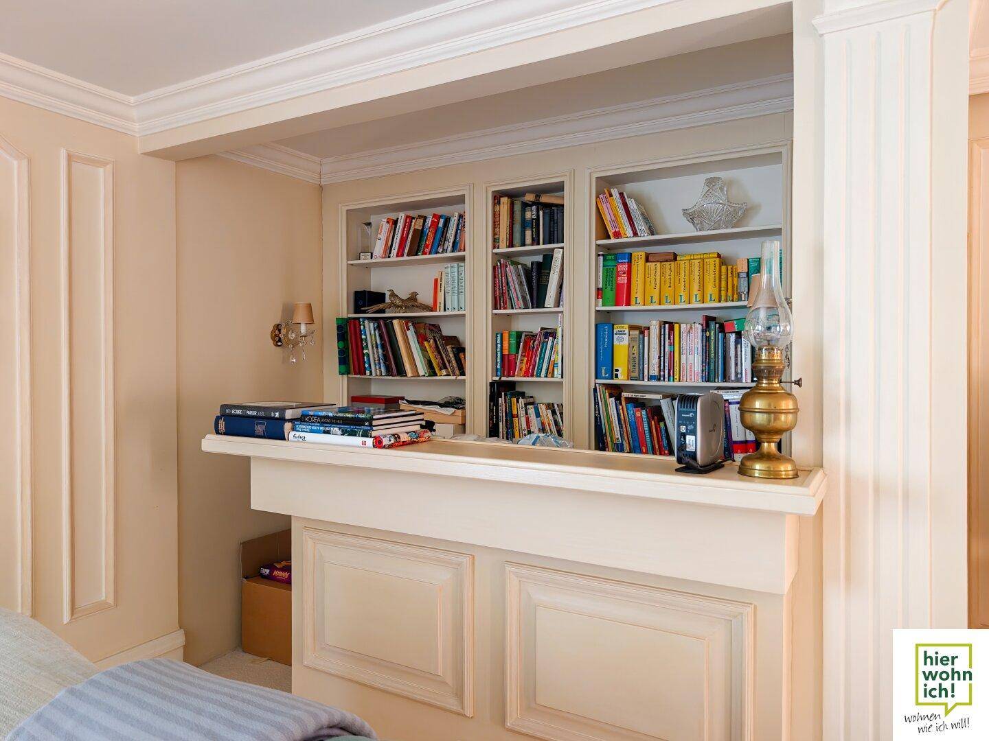 Eingebautes Bücherregal mit dekorativer Ablage und klassischer Beleuchtung.