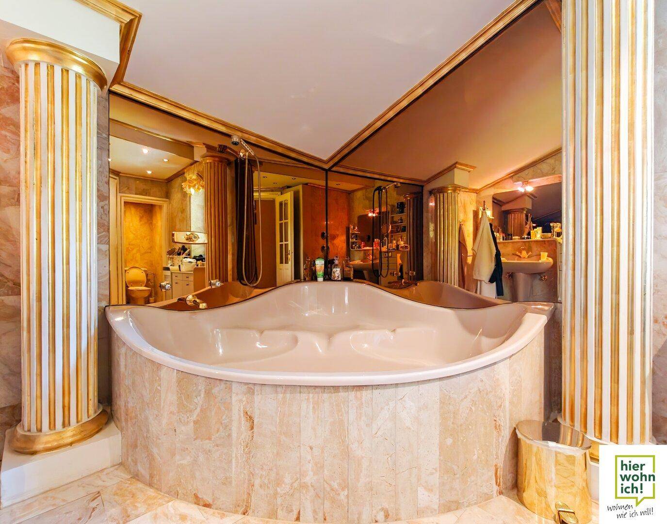 Großzügiges Badezimmer mit Eckbadewanne, Marmorverkleidung und goldenen Akzenten.