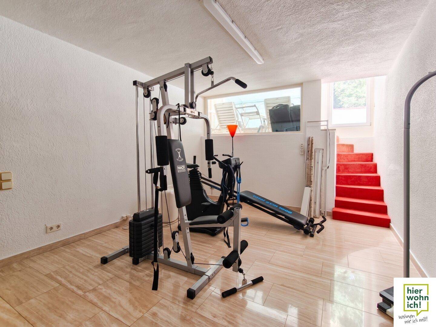 Fitnessraum im Untergeschoss mit Trainingsgeräten und Blick nach draußen.