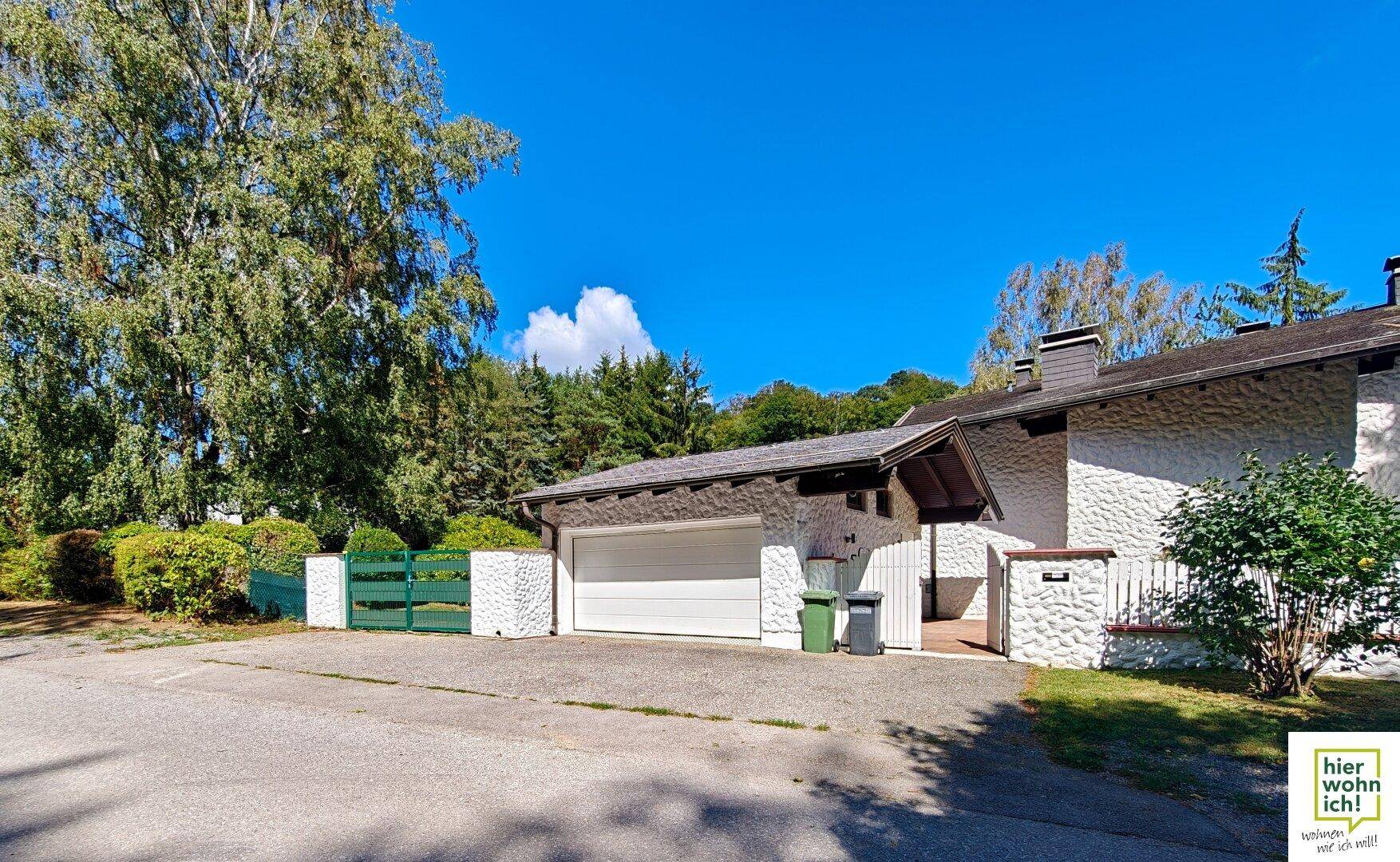 Einfahrt zu einem Haus mit Garage und gepflegtem Vorgarten.