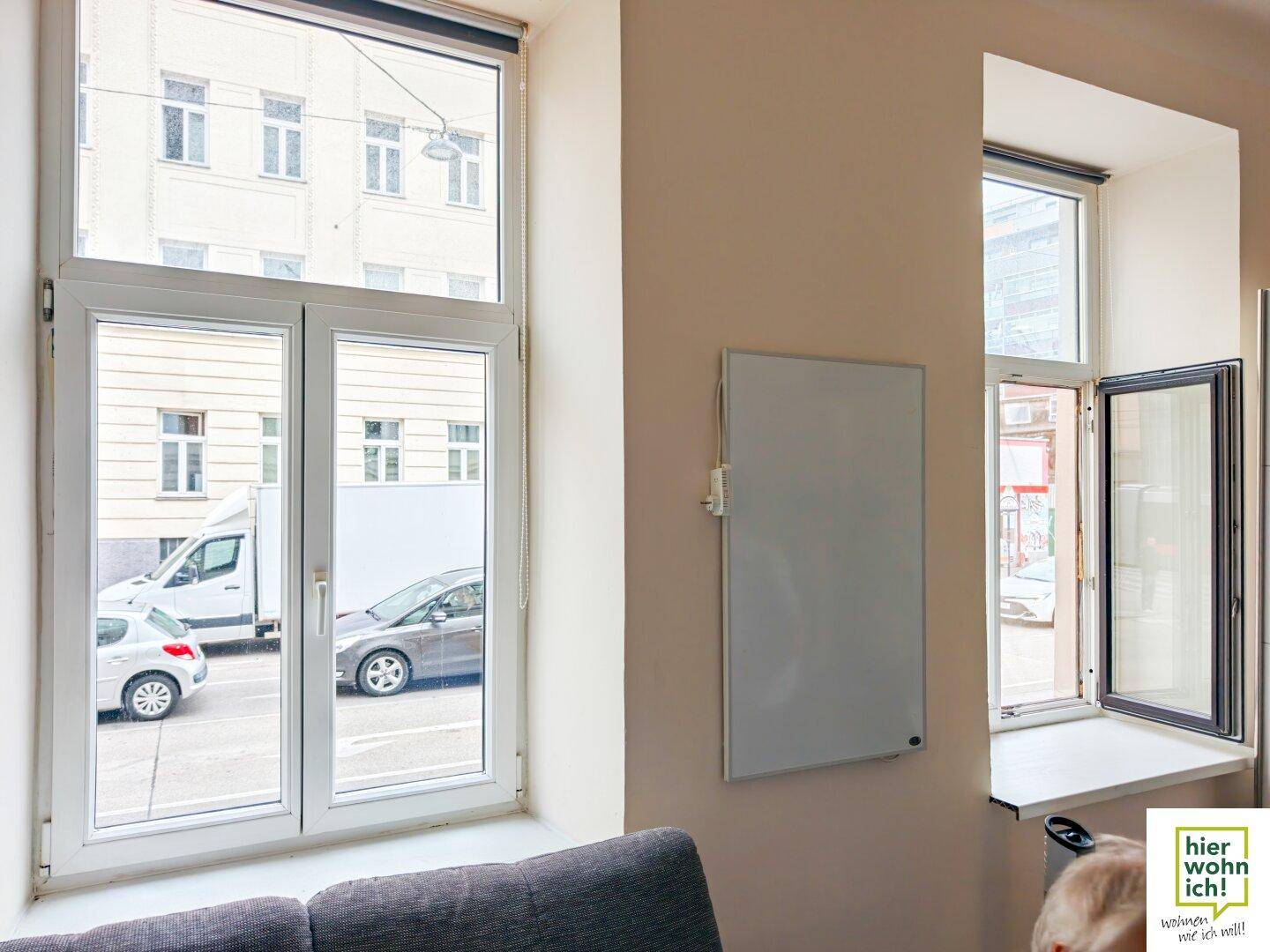 Nahaufnahme der Fenster im Wohnzimmer mit Blick auf die Straße und gegenüberliegende Gebäude.
