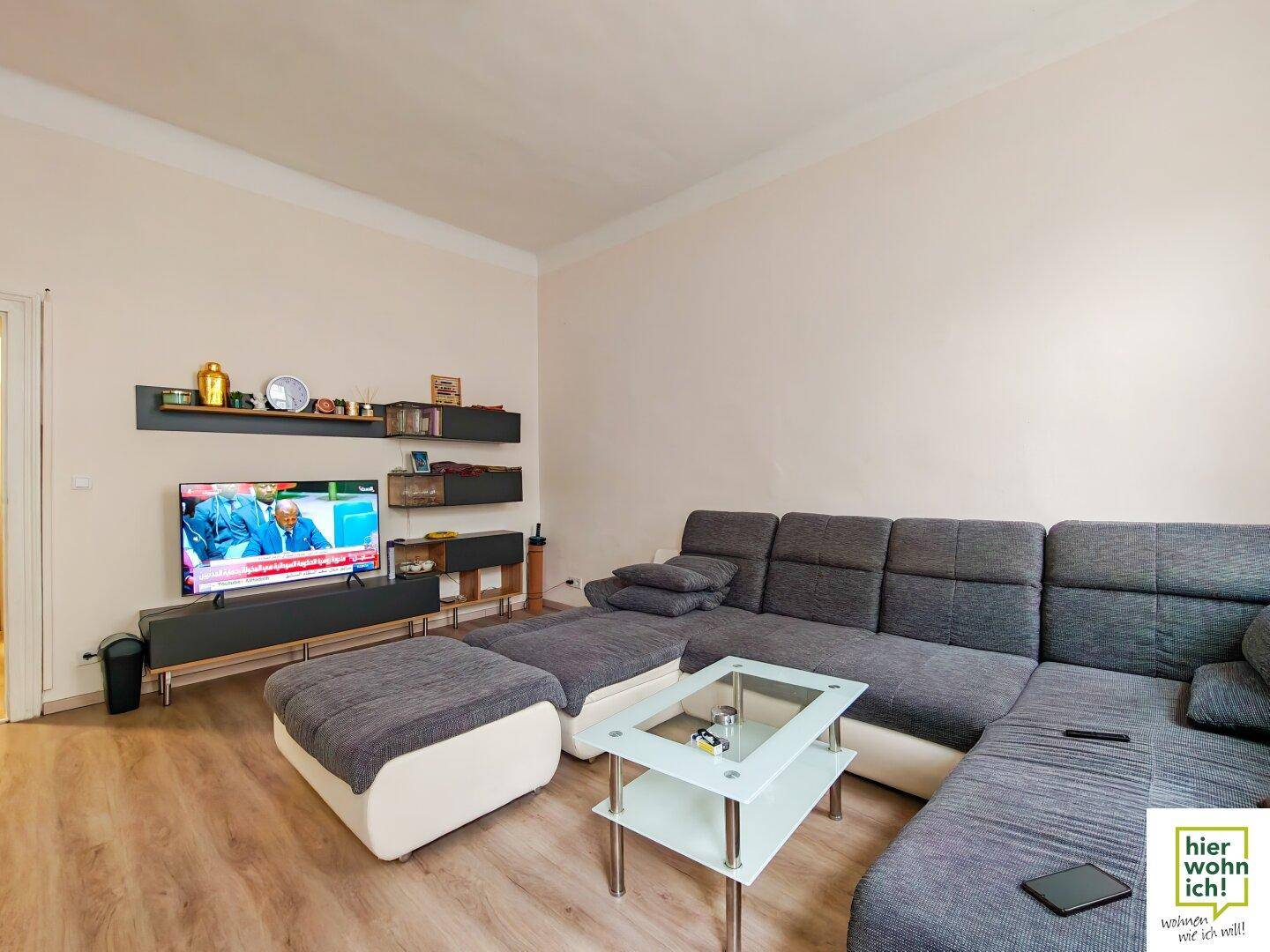 Gemütliches Wohnzimmer mit großem Ecksofa, Fernseher und Wandregalen für Dekoration.