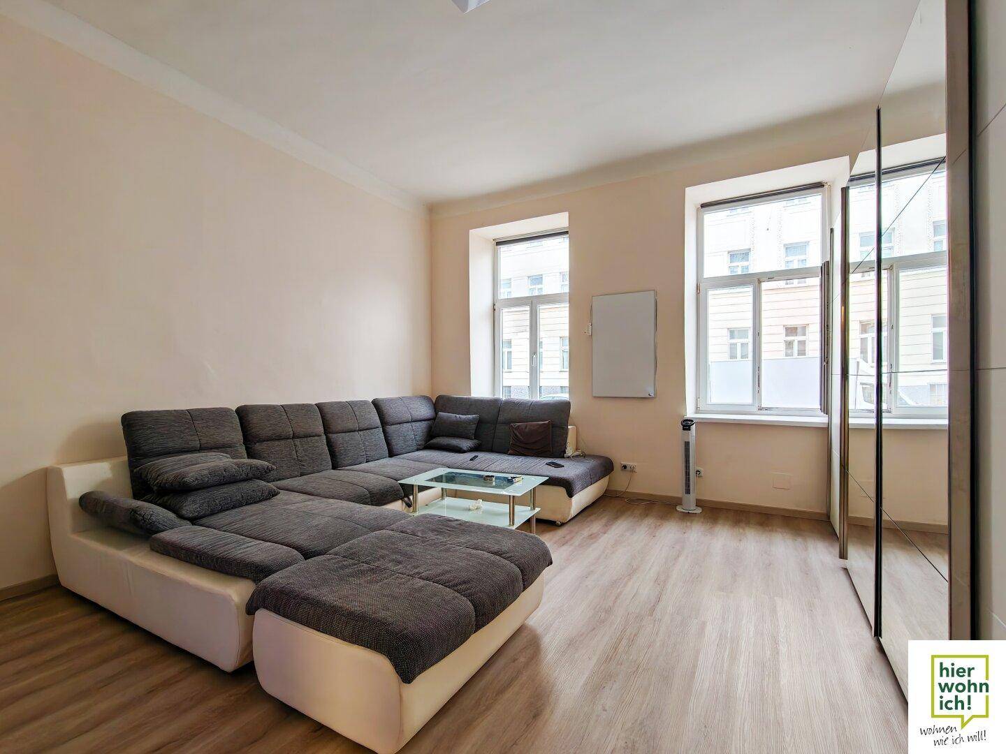 Geräumiges Wohnzimmer mit großem Ecksofa, Couchtisch und Spiegelschränken, die den Raum optisch erweitern.