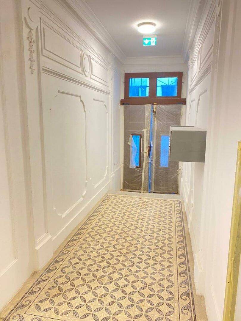 Eleganter Flur mit aufwendigen Stuckverzierungen an den Wänden und einem kunstvollen Fliesenboden.