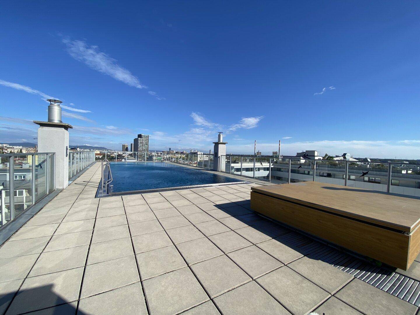 Weitläufige Dachterrasse mit Poolbereich und weitem Blick über die Stadtlandschaft.
