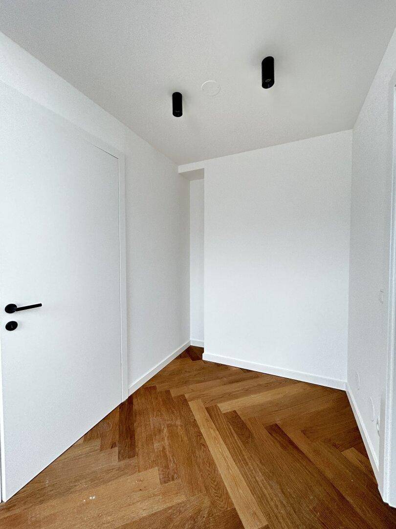 Heller Flur mit Fischgrätparkett und weißen Wänden, bereit für die Einrichtung.