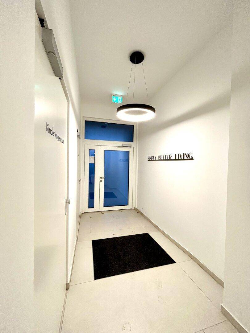 Heller Flur mit modernen Fliesen und Zugang zu einem Kinderwagenraum.