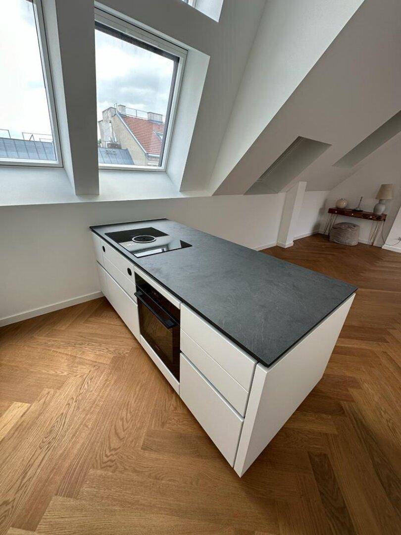 Kücheninsel mit integriertem Induktionskochfeld und Backofen in einer modernen Dachgeschosswohnung.