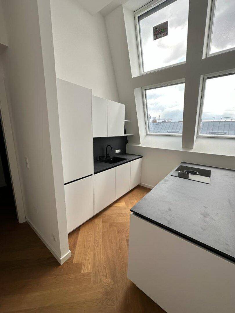 Helle, moderne Küche mit weißen Schränken, dunkler Arbeitsplatte und integriertem Spülbecken.