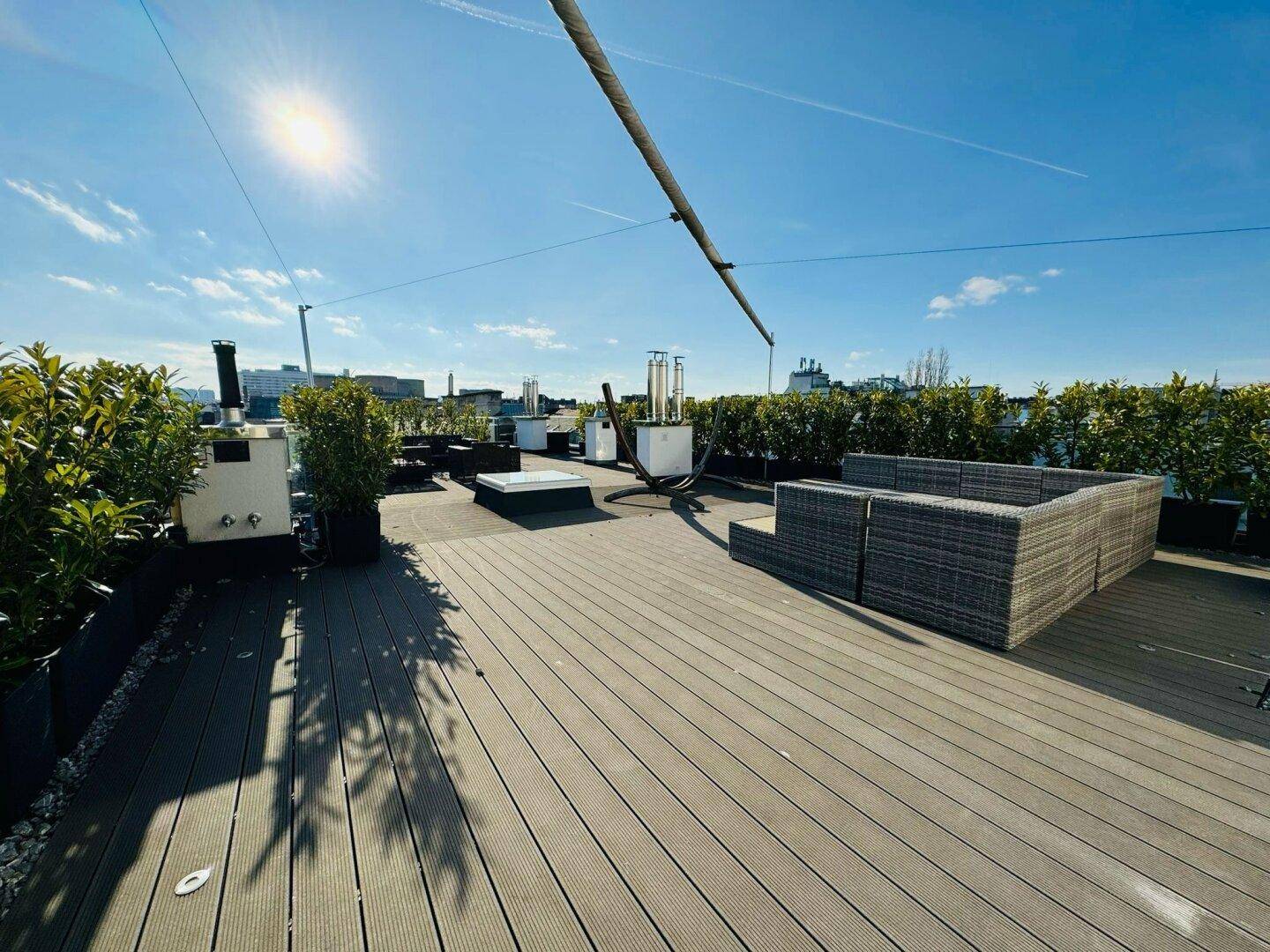 Geräumige Dachterrasse mit Lounge-Möbeln, Pflanzen und weitem Blick über die Stadt.