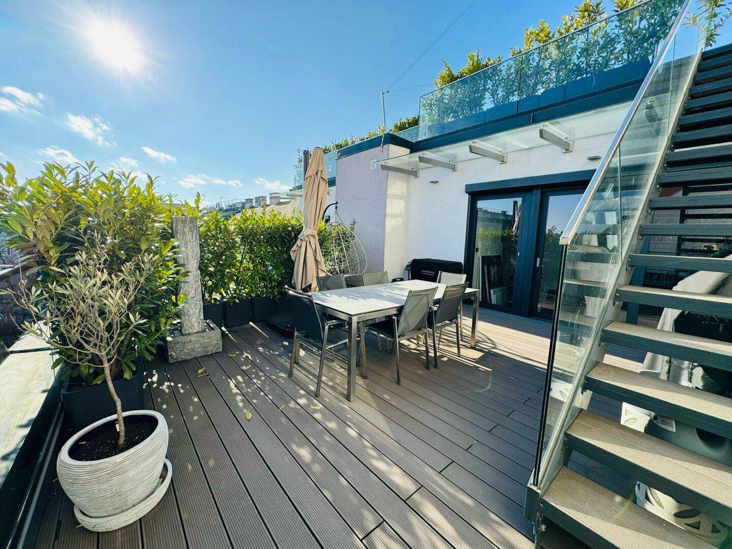 Untere Dachterrasse mit Esstisch, Grillbereich und Treppe zur oberen Ebene.