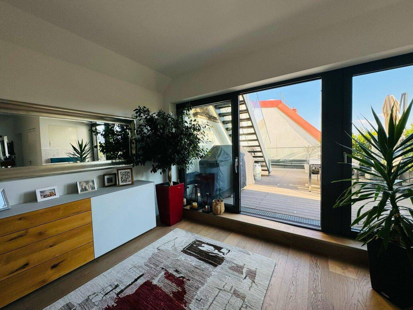Heller Raum mit großem Schiebetürzugang zu einer sonnigen Terrasse und Holzboden.