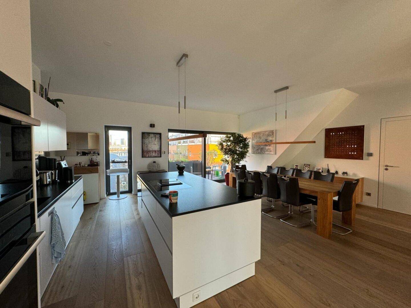 Moderne Kücheninsel und Essbereich mit Holztisch, offenem Grundriss und hellem Ambiente.