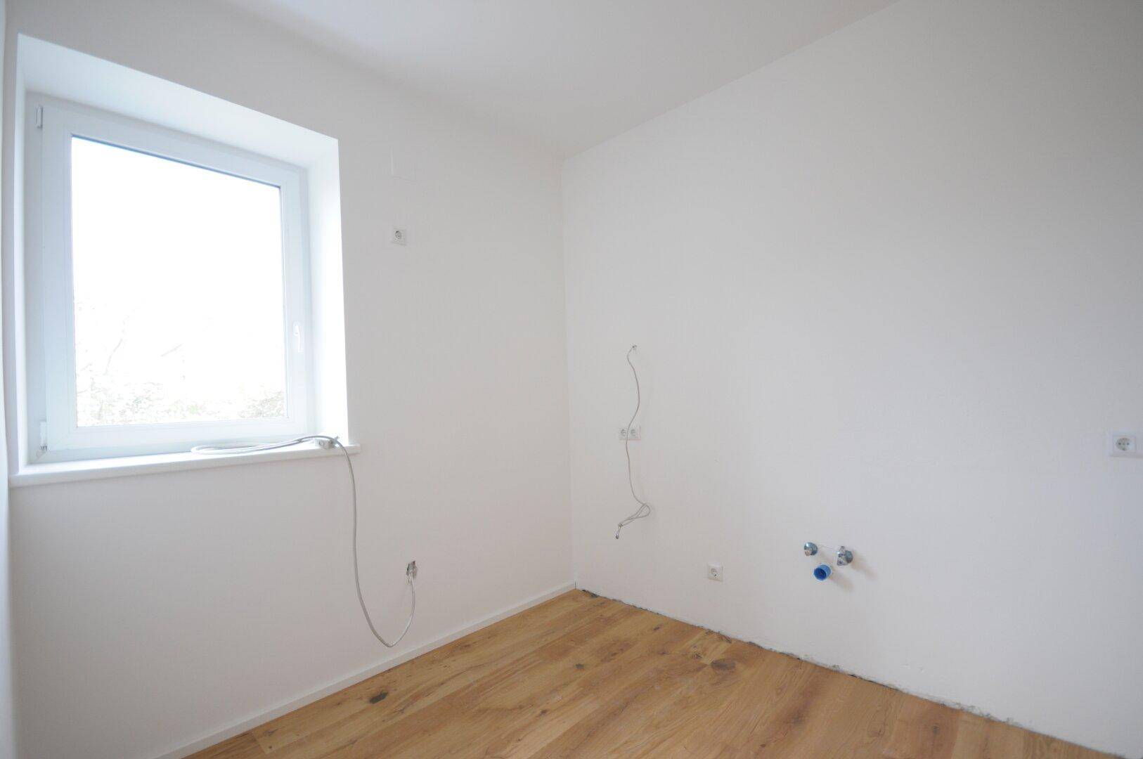 Unmöbliertes Schlafzimmer mit hellem Holzboden und einem großen Fenster für viel Licht.