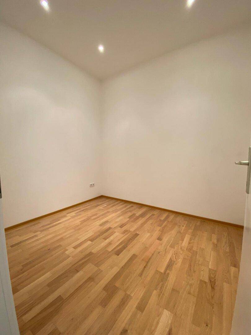 Kleiner, heller Raum mit Parkettboden und weißen Wänden, vielseitig nutzbar.