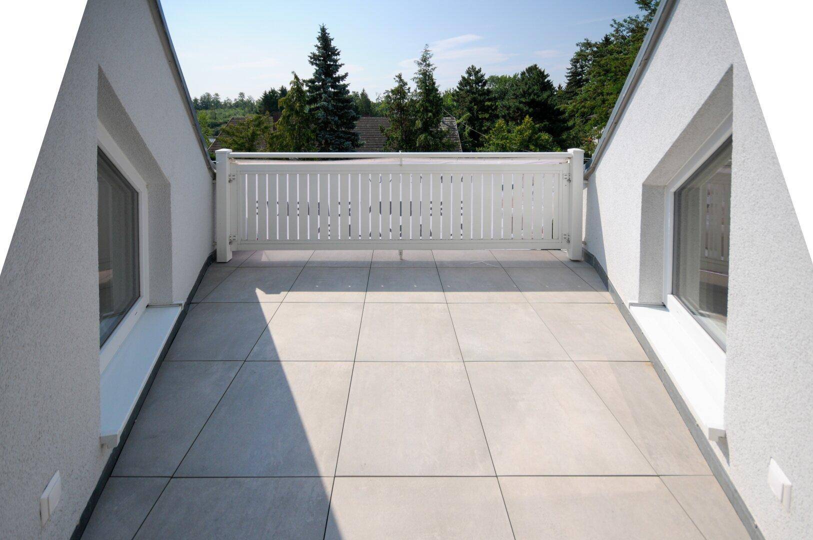Große Dachterrasse mit weißem Geländer und Blick ins Grüne, ideal zum Entspannen im Freien.