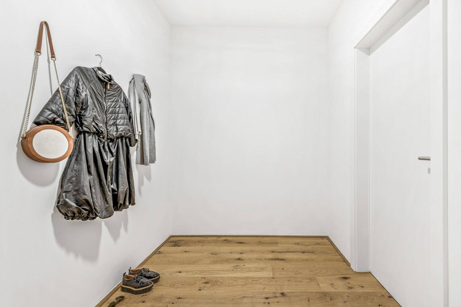 Heller Flur mit Holzboden und Garderobe, ideal für den Empfang von Gästen.