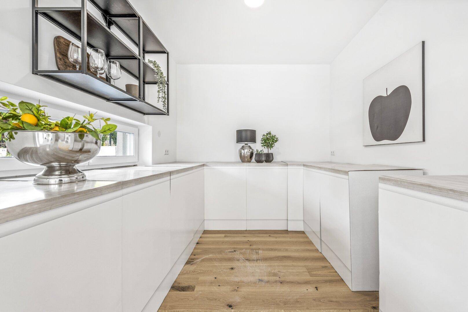 Moderne, helle Küche mit weißen Schränken, Holzarbeitsplatten und Fenster.