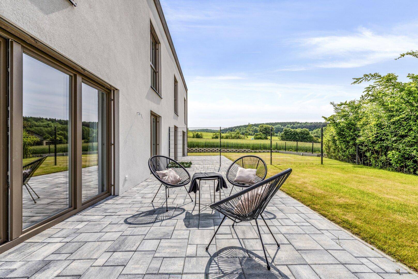 Geräumige Terrasse mit Gartenmöbeln und weitem Blick über die Landschaft.