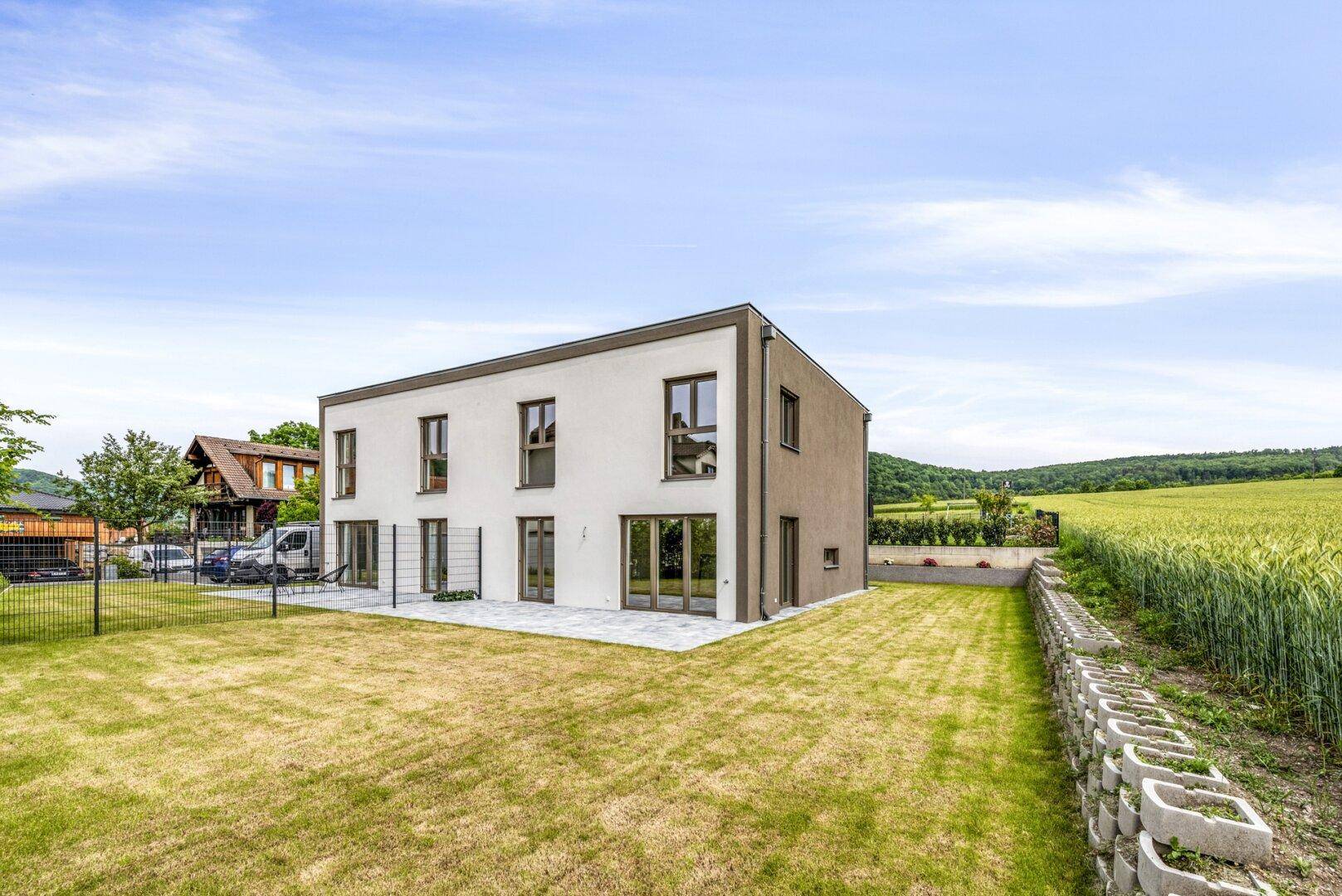 Modernes Reihenhaus mit großem Garten und Blick auf die umliegende Natur.