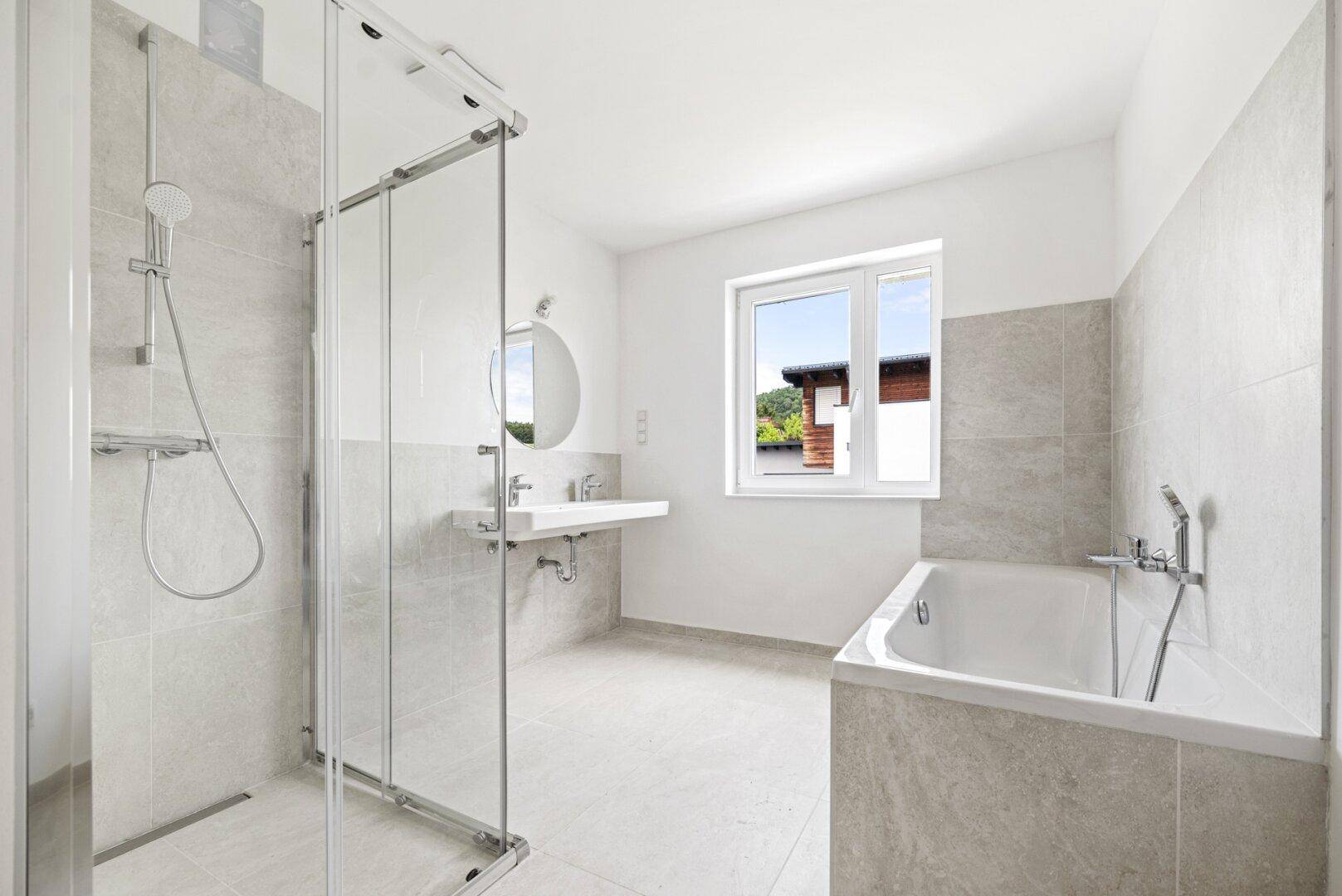 Helles Badezimmer mit Badewanne, Dusche, Einzelwaschbecken und Fenster.