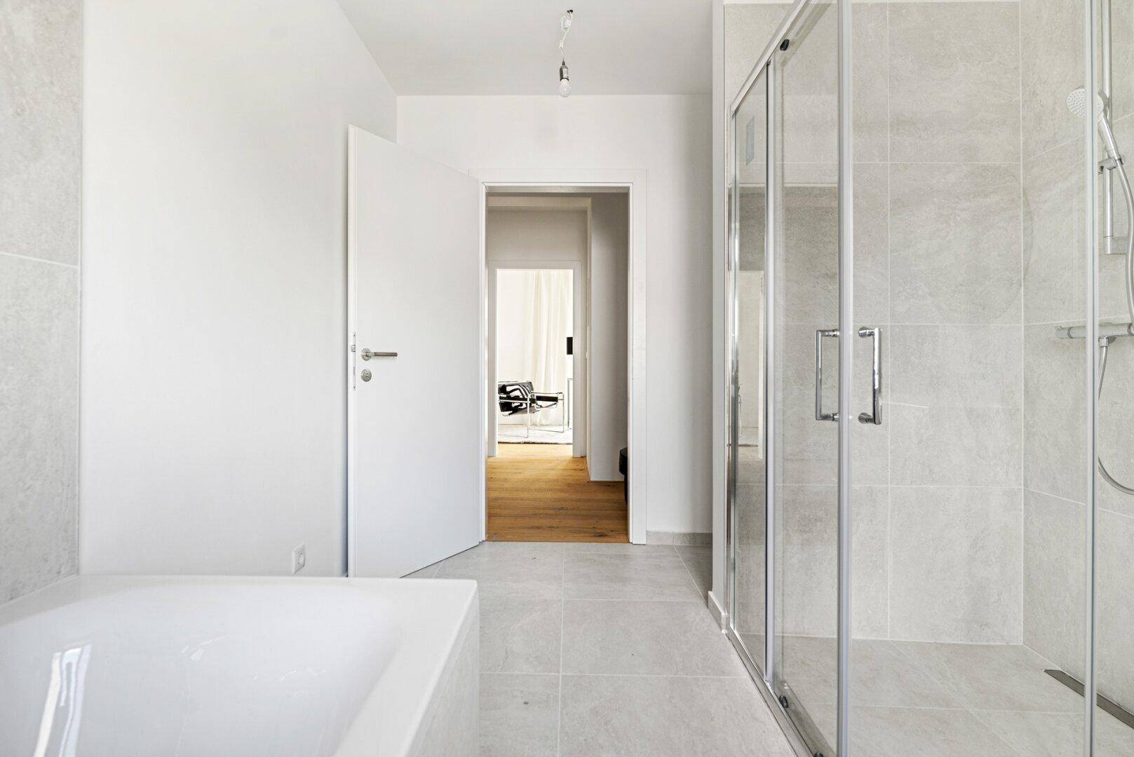 Modernes Badezimmer mit Dusche, Badewanne und hellen Fliesen.