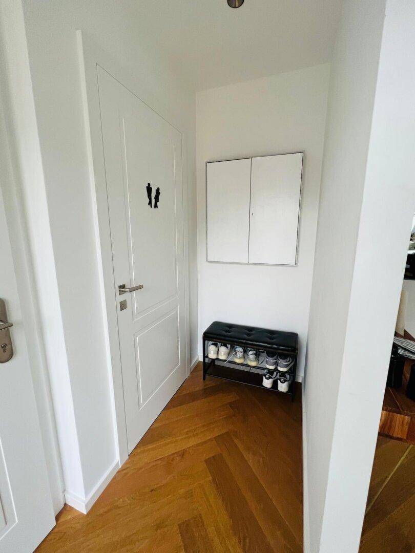 Heller Flur mit Parkettboden und einer modernen Schuhbank neben der Tür.