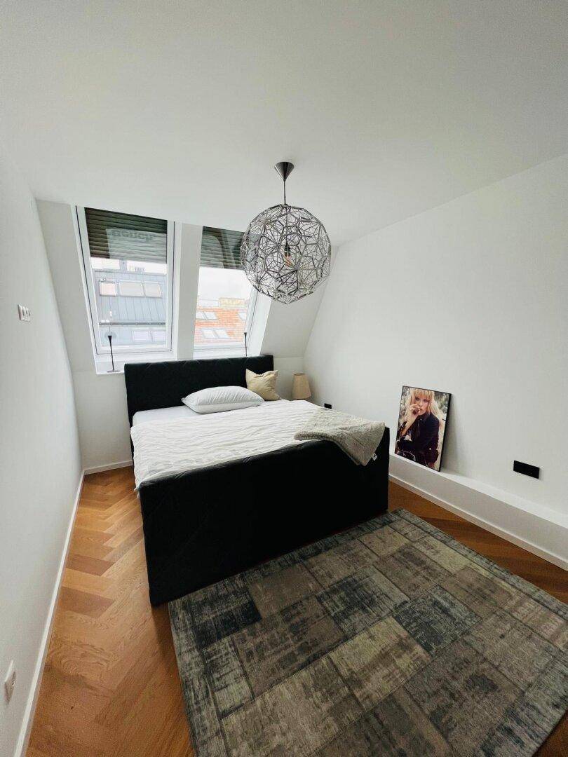 Modernes Schlafzimmer mit Parkettboden, Dachfenstern und stilvoller Deckenleuchte.