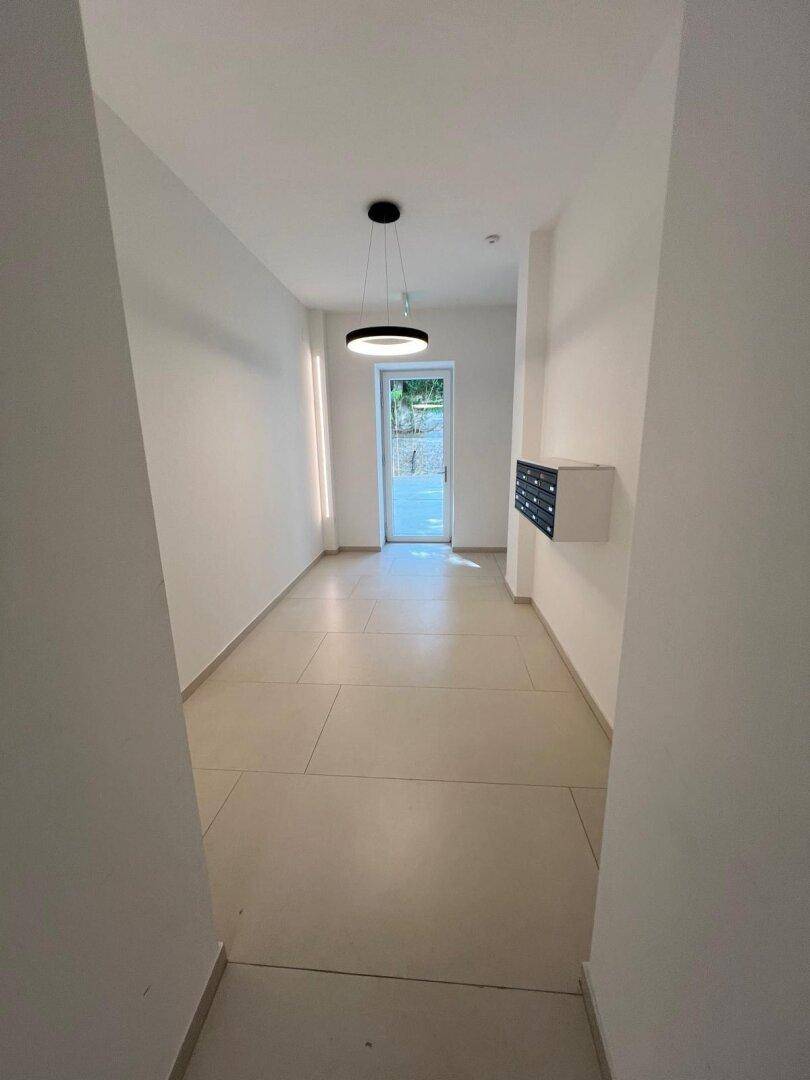 Heller Eingangsbereich mit modernen Fliesen und Postfächern in einem Neubau.