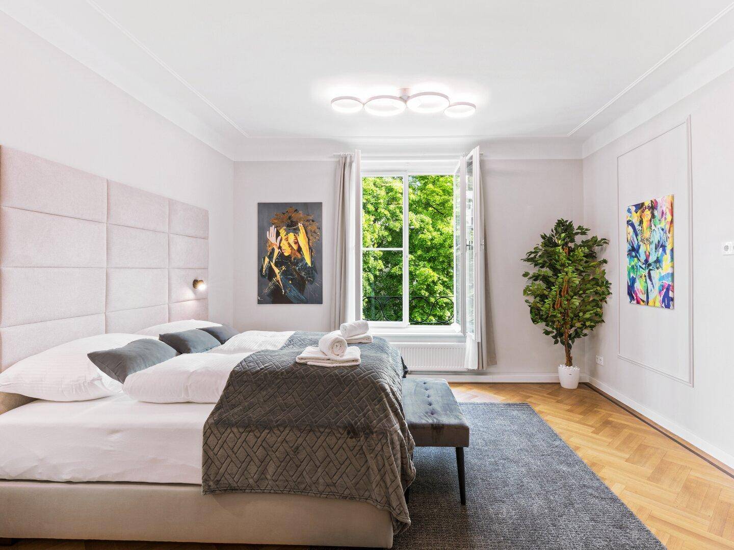 Geräumiges Schlafzimmer mit bequemen Bett, Parkettboden und moderner Deckenbeleuchtung.