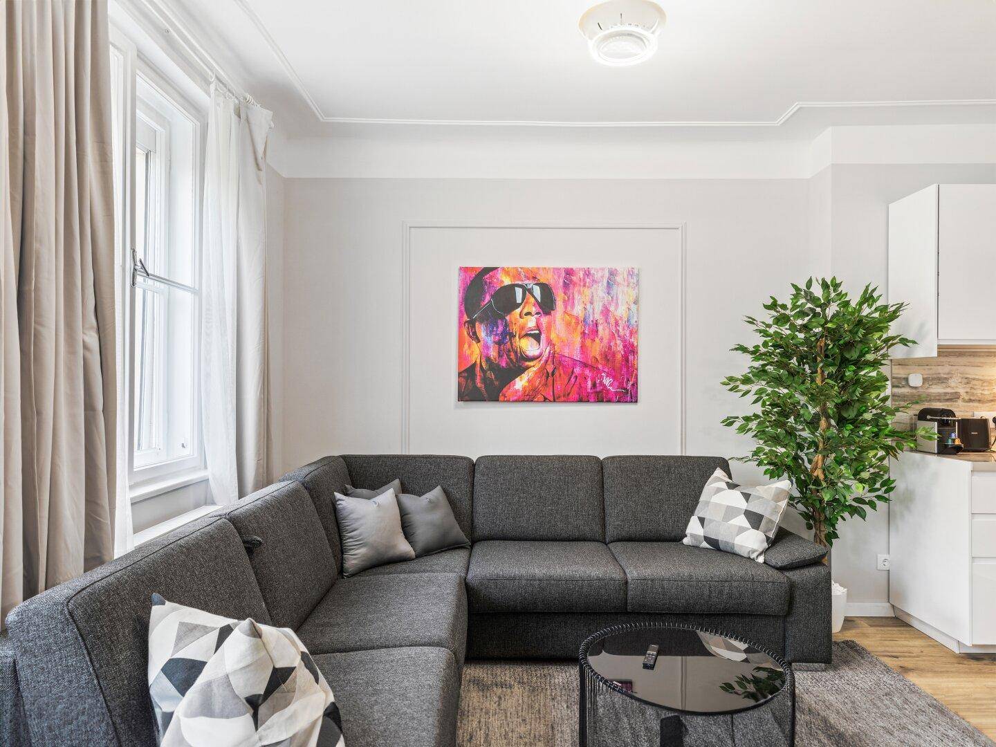 Gemütliches Wohnzimmer mit großem Ecksofa, modernem Kunstwerk und viel Tageslicht.