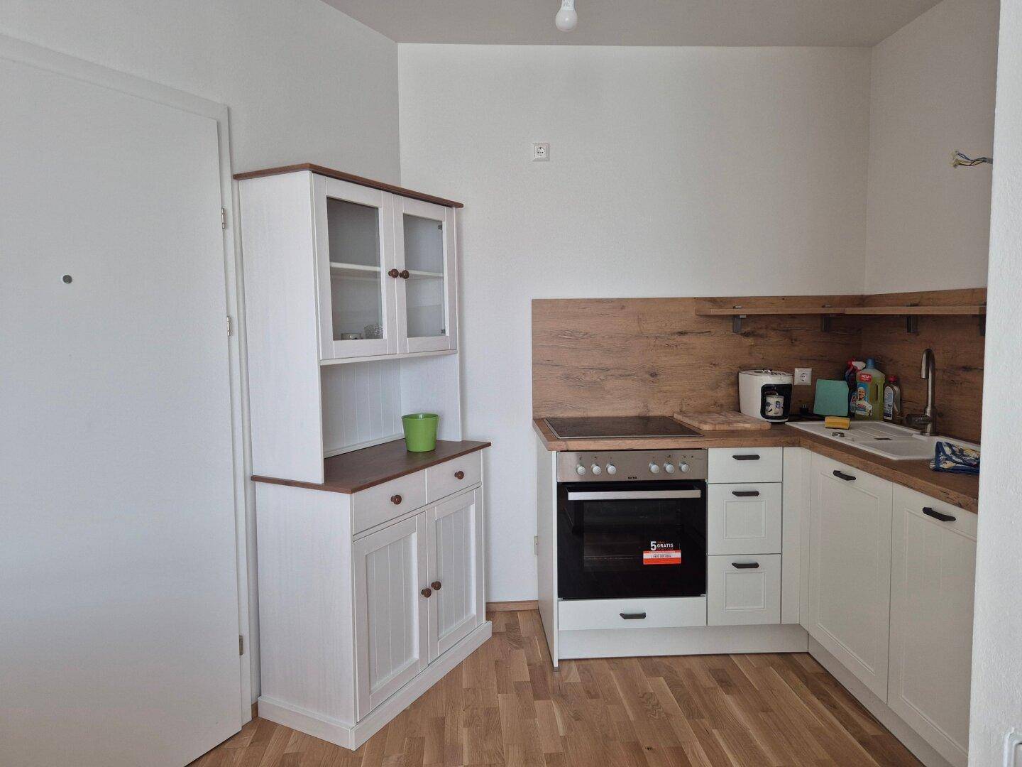 Kleine Küche mit weißen Schränken, Holzoptik-Arbeitsplatte und einem zusätzlichen Buffet-Schrank.