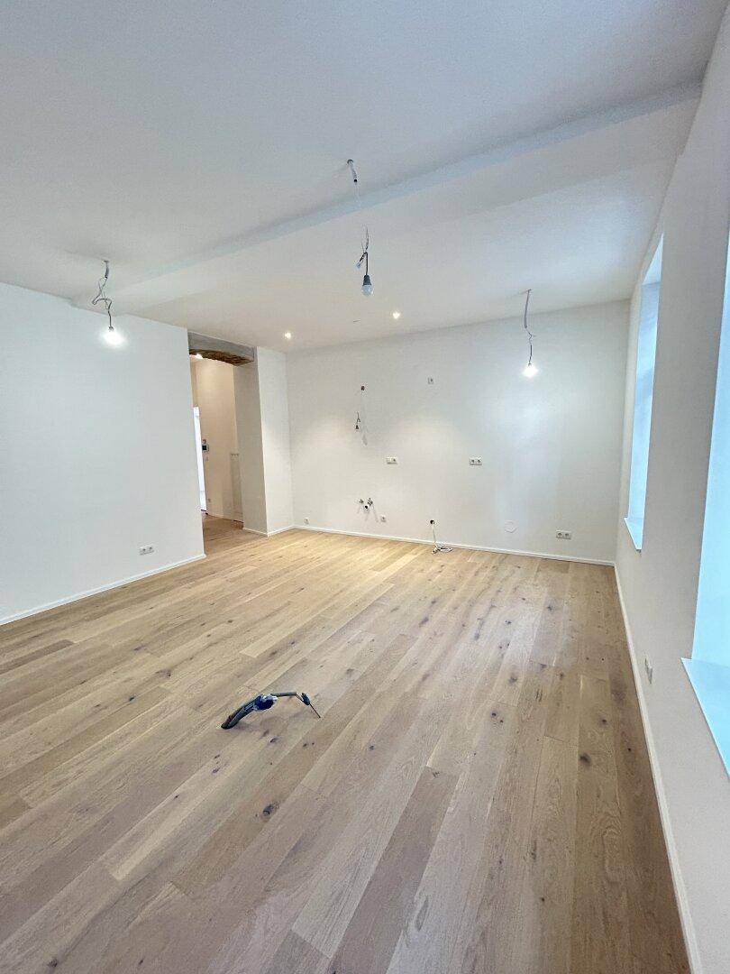 Heller, leerer Raum mit neu verlegtem Holzparkett und weißen Wänden, bereit für die Einrichtung.