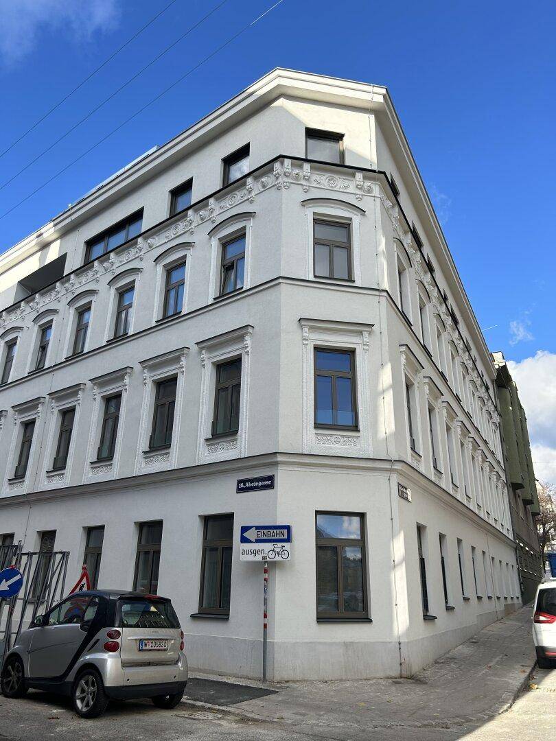 Eckgebäude mit weißer Fassade, vielen Fenstern und traditionellen architektonischen Details.