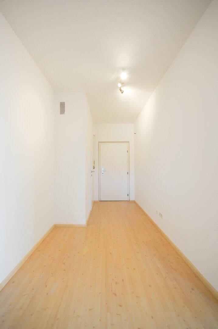 Langer, heller Flur mit Parkettboden, der den Eingangsbereich mit den Wohnräumen verbindet.