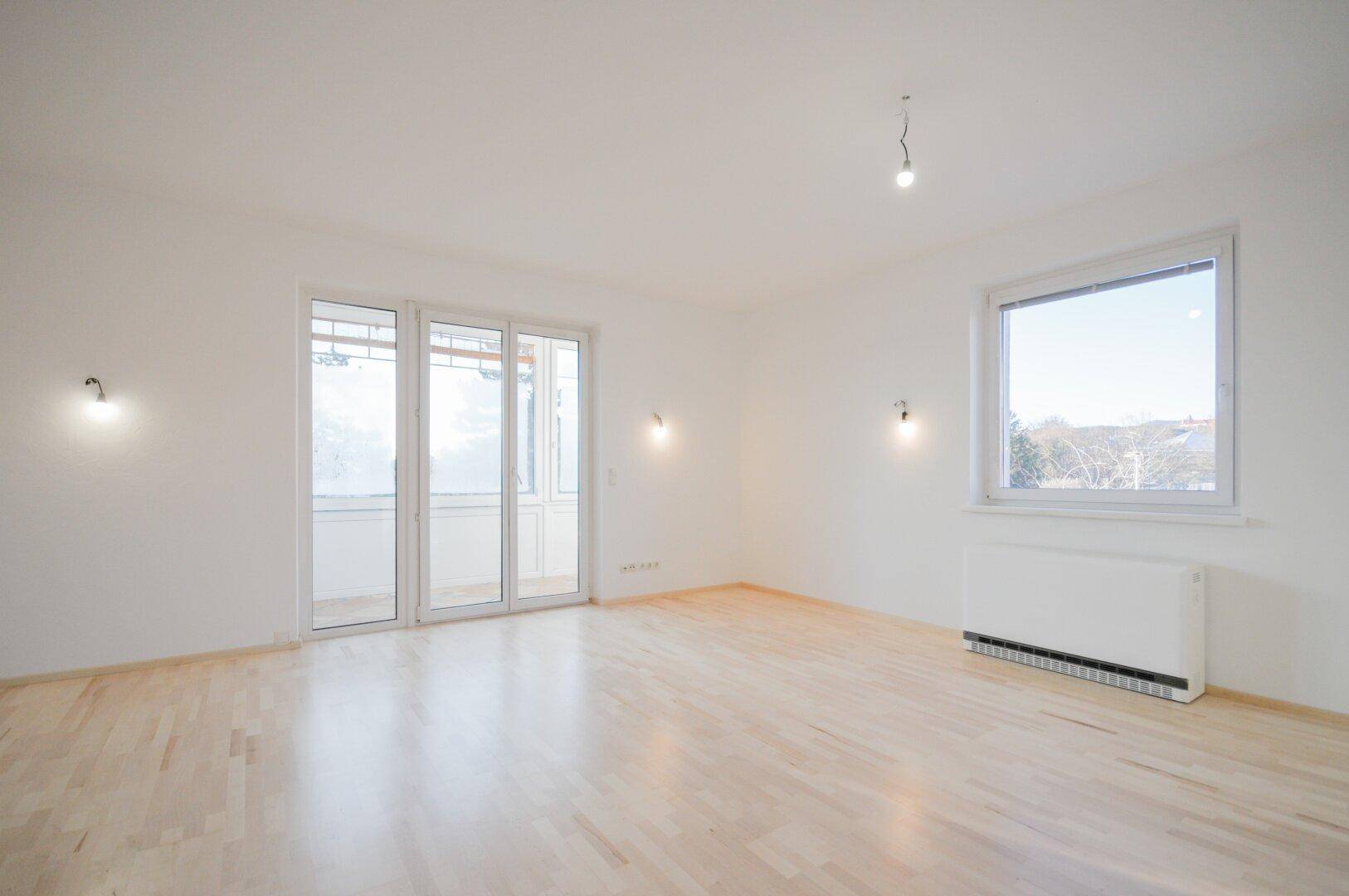 Geräumiges, helles Wohnzimmer mit Parkettboden und großem Fenster, bereit zur individuellen Gestaltung.