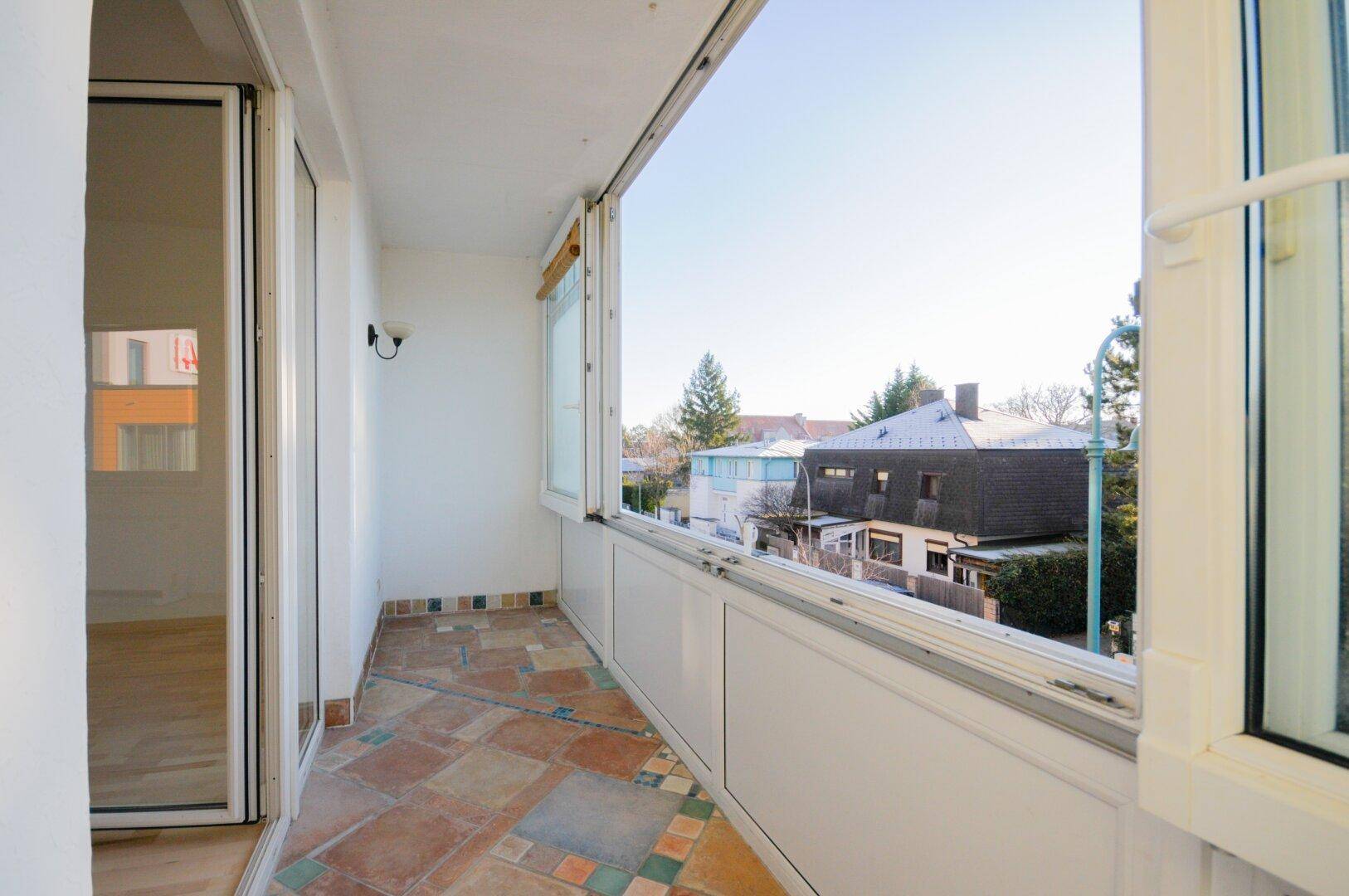 Schmaler Balkon mit Terrakotta-Fliesen und weitem Blick über die Dächer der Nachbarschaft.
