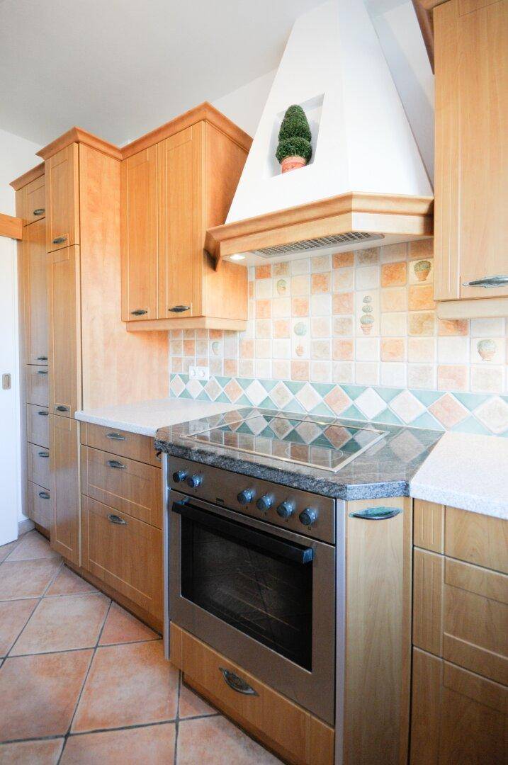 Einbauküche mit Holzfronten, Granitarbeitsplatte und integriertem Backofen und Kochfeld.