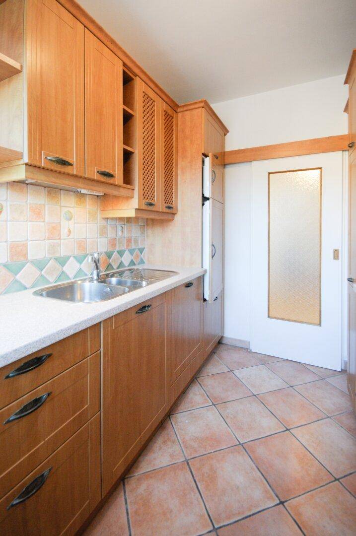 Küche mit Holzschränken, Terrakotta-Fliesen und integriertem Kühlschrank, der sich hinter einer Tür verbirgt.