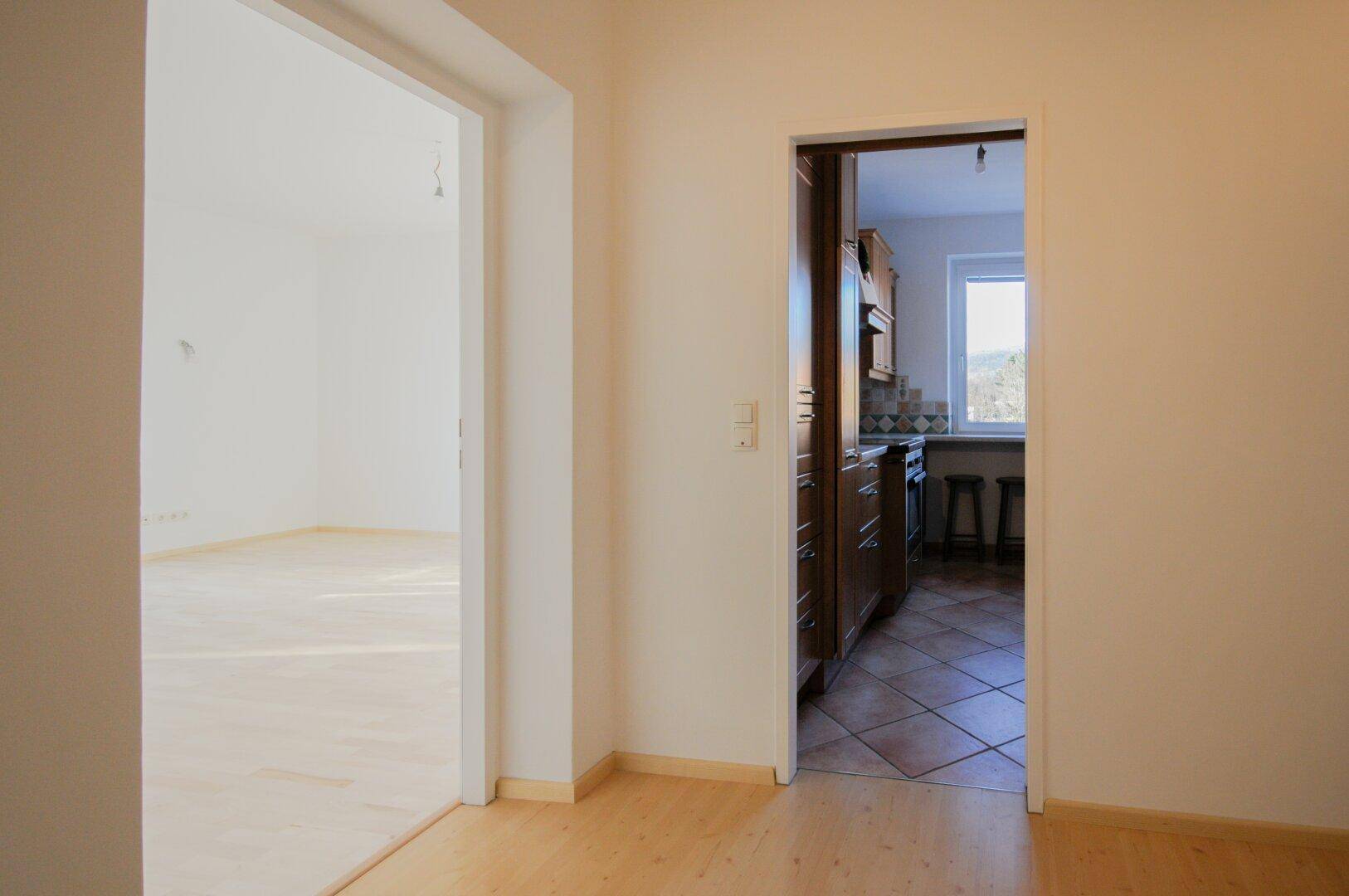 Heller Flur mit Parkettboden, der den Wohnbereich mit der Küche verbindet.